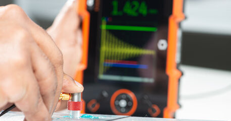 操作員使用Krautkr?mer CL Go+超聲波精密測(cè)厚儀檢測(cè)金屬樣件，適用于航空航天、汽車等行業(yè)的無(wú)損檢測(cè)需求。