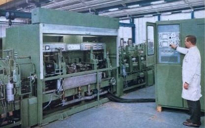 一位穿白大褂的男子在工廠中操作大型工業(yè)機器。