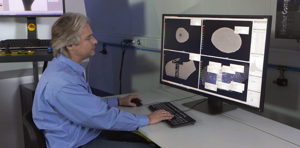 工程師在實(shí)驗(yàn)室中使用無損檢測(cè)（NDE）軟件分析CT掃描數(shù)據(jù)，屏幕顯示多個(gè)材料內(nèi)部結(jié)構(gòu)圖像
