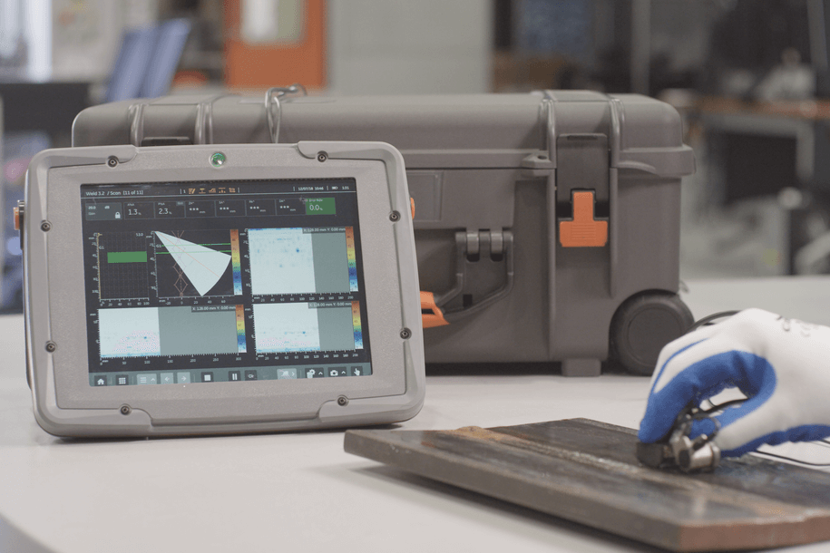 一只戴手套的手在工業(yè)實驗室環(huán)境中使用裝有保護外殼的堅固平板設(shè)備，其觸摸屏顯示器用于檢查和數(shù)據(jù)分析。