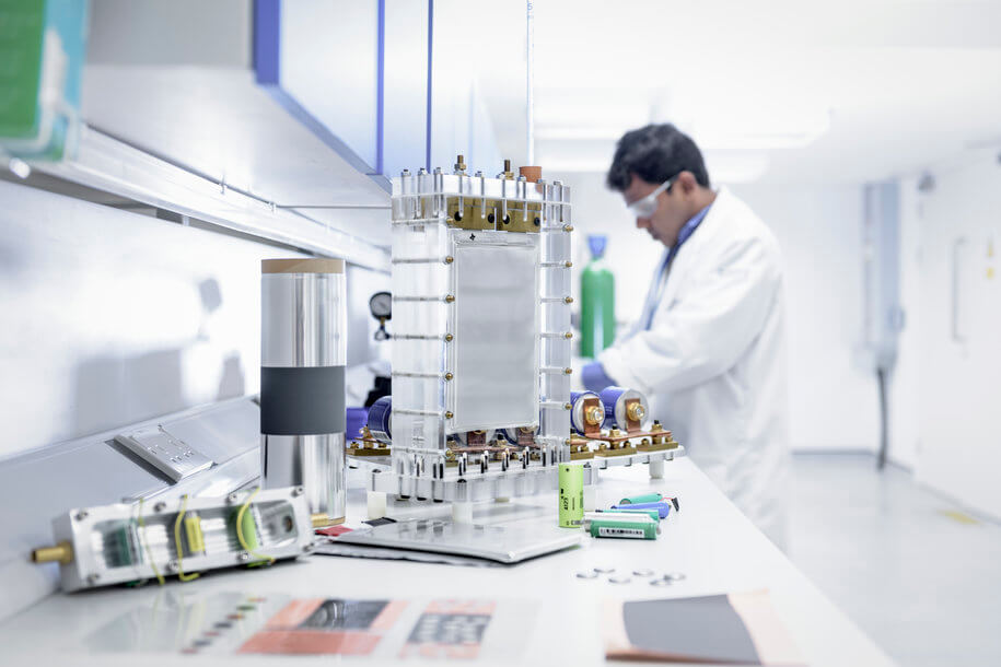 研究員在實(shí)驗(yàn)室中進(jìn)行鋰離子電池測試，桌面展示多種電芯樣本與測試設(shè)備，用于新能源電池研發(fā)與質(zhì)量驗(yàn)證。